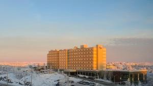a large yellow building with snow on the ground at The Explorer Hotel in Yellowknife