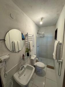 a bathroom with a sink and a toilet and a mirror at Pouso Sabiá Suítes in Paraty
