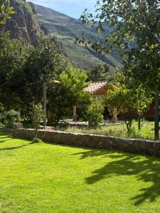 a green yard with a house and mountains in the background at Casa De Aida in Calca