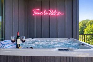 a tub with two glasses of wine and a sign that reads time to relax at Firefly Lodge - Pool, Theatre, Dog Friendly! in Pigeon Forge