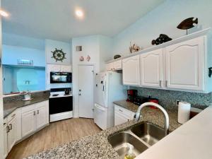 a kitchen with white cabinets and a white refrigerator at Shipwrecked Getaway For 6 in Galveston
