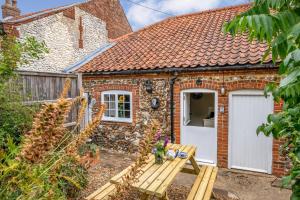 a brick cottage with a white door and a bench at 2 Bed in Burnham Overy Staithe oc-p30460 in Burnham Market