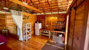 a kitchen in a wooden cabin with a refrigerator at RAIATEA - Orion Pool Bungalow in Uturoa