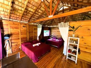 a bedroom with two beds in a room with wooden walls at RAIATEA - Orion Pool Bungalow in Uturoa