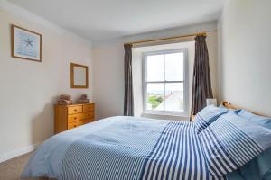 a bedroom with a blue and white bed and a window at 2 Bed in Mousehole oc-mizpah in Mousehole