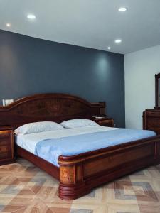 a bedroom with a wooden bed with a blue wall at Thiago Hotel campestre in Armenia