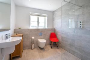 a bathroom with a toilet and a sink and a red chair at 3 Bed in Chatton oc-nb1987 in Chatton +9 photos