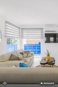 a white living room with a couch and a table at The blue wave in Willemstad