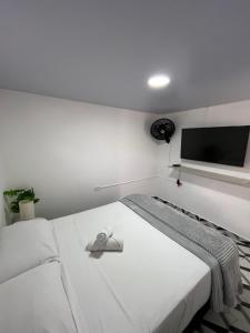 a white bedroom with a bed with a flat screen tv at Apartamento en Itagüí in Itagüí