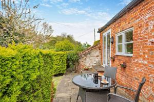 a patio with a table and chairs and a brick building at 1 Bed in Barton Turf oc-s29126 in Neatishead
