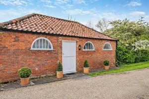a brick house with a white door and two windows at 1 Bed in Barton Turf oc-s29126 in Neatishead +4 photos