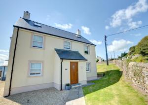 a white house with a brown door and a stone wall at 5 Bed in Amroth oc-pw9068 in Amroth