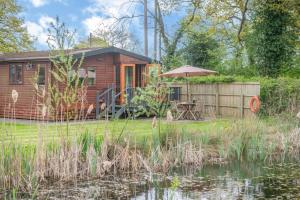 a wooden cabin with an umbrella next to a pond at 2 Bed in Otley oc-slm in Burgh