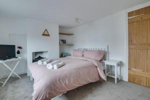 a bedroom with a bed with pink sheets and a television at 2 Bed in Aldeburgh oc-3al in Aldeburgh