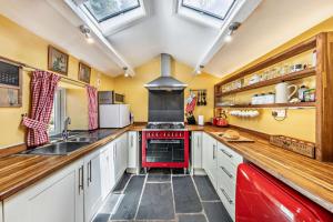 a kitchen with white cabinets and a red stove at 3 Bed in Fucheswen oc-m29608 in Blaenau-Ffestiniog