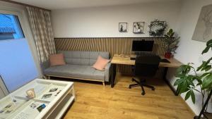 a living room with a couch and a desk with a computer at Pension Schmidt - Schwarzwaldnest - voll ausgestattetes Apartment in Häusern +5 photos