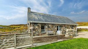 a stone house with a bench on a porch at 2 Bed in Reef oc-r30133 in Uig