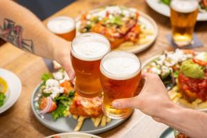 two people holding glasses of beer on a table with food at Royal Hotel Tumut in Tumut +16 photos