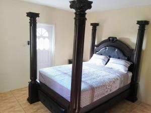a bedroom with a bed with a wooden frame at The Cupid Chalet Suite in Kingstown