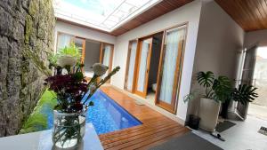 a room with a swimming pool and a vase of flowers at Genta Villa Bali in Sanur