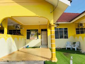 a yellow house with a porch with two chairs at Olive Cottage in Marang