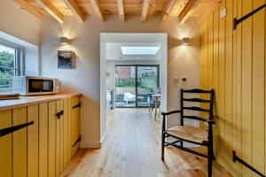 a kitchen with wooden cabinets and a microwave and a chair at 1 Bed in Syderstone oc-c29233 in Syderstone