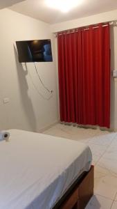 a bedroom with red curtains and a tv on the wall at Casa Excalibur in Máncora