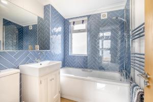 a bathroom with blue tiled walls and a tub and a sink at 2 Bed in Tallington oc-b32208 in Barholm +10 photos