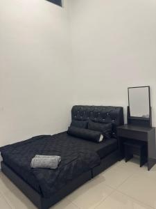 a bed with a black leather headboard and a table at RNA Homestay Bayan in Tawau