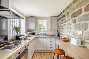 a kitchen with white cabinets and a stone wall at 1 Bed in Warslow oc-h27591 in Warslow
