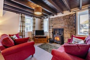 a living room with two red chairs and a fireplace at 2 Bed in Langthwaite oc-c30568 in Low Eskcleth