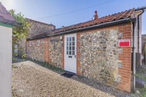 a brick building with a white door and a wall at 2 Bed in Sheringham oc-2310 in Sheringham