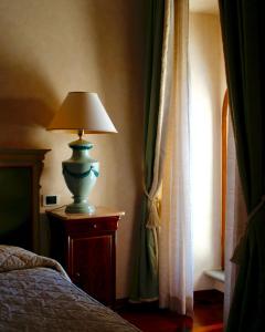 una lampada seduta su un tavolo accanto a un letto di Relais Ducale a Gubbio