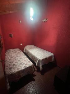two beds in a room with a red wall at Casona de Montaña in Los Hornillos