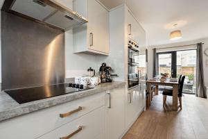 a kitchen with white cabinets and a dining table at 3 Bed in Ilfracombe oc-s29585 in Ilfracombe