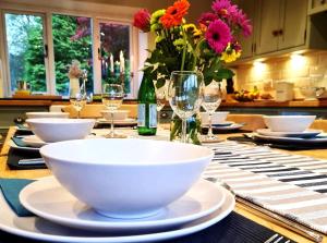 a table with bowls and glasses and a vase of flowers at 4 Bed in Little Hayfield oc-c31097 in Hayfield