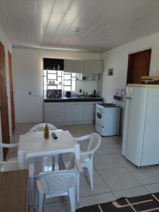 a kitchen with a table and chairs and a white refrigerator at Pousada do Coqueiro in São Gabriel
