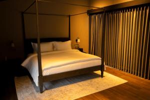 a bedroom with a canopy bed with a white bedspread at Spring River Cisarua in Paragajen +20 photos