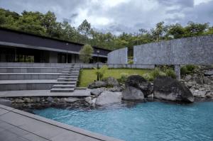 a house with a pond in front of a building at Spring River Cisarua in Paragajen