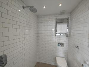 a white tiled bathroom with a toilet and a sink at 2 Bed in Craster oc-c25099 in Craster +12 photos