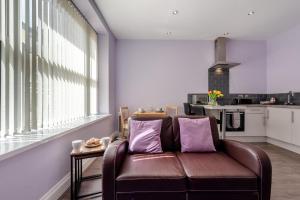 a living room with a brown leather couch and a kitchen at 1 Bed in Tenby oc-w28984 in Tenby