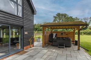 a pergola on a patio next to a house at 4 Bed in Saham Toney oc-o30348 in Saham Toney