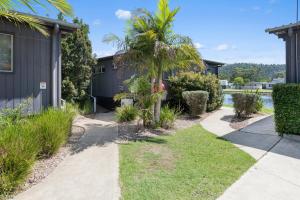 a house with a palm tree next to a sidewalk at Ingenia Holidays Lake Conjola in Conjola