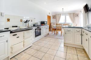 a large kitchen with white cabinets and a table at 3 Bed in Southerndown oc-l10852 in Southerndown +20 photos
