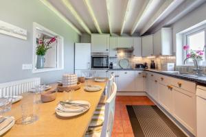 a kitchen with a wooden table with plates and glasses at 4 Bed in St. Brides oc-o30488 in Saint Brides