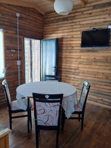 a dining room with a table and chairs and a flat screen tv at Cabaña Doña Loly in Olavarría