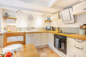 a kitchen with white cabinets and a wooden table at 2 Bed in Kirkcudbright oc-a30803 in Kirkcudbright