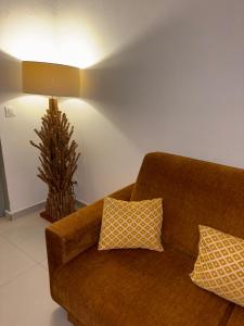 a brown couch with two pillows in a living room at Logement « Indigo » in Capesterre +1 photo
