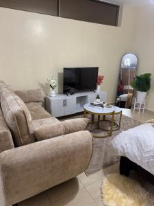 a living room with a couch and a tv at Alyahomes in Nairobi