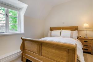 a bedroom with a wooden bed and a window at 2 Bed in Winchcombe oc-t32023 in Winchcombe